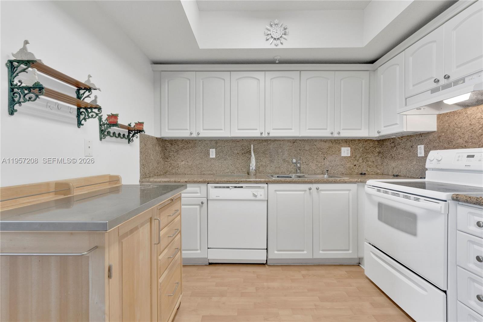 3500 Coral Way, Unit 710 Miami, FL 33145 - Photo 11 of 43 Efficient kitchen featuring clean white cabinetry, granite countertops, and a functional workspace.
