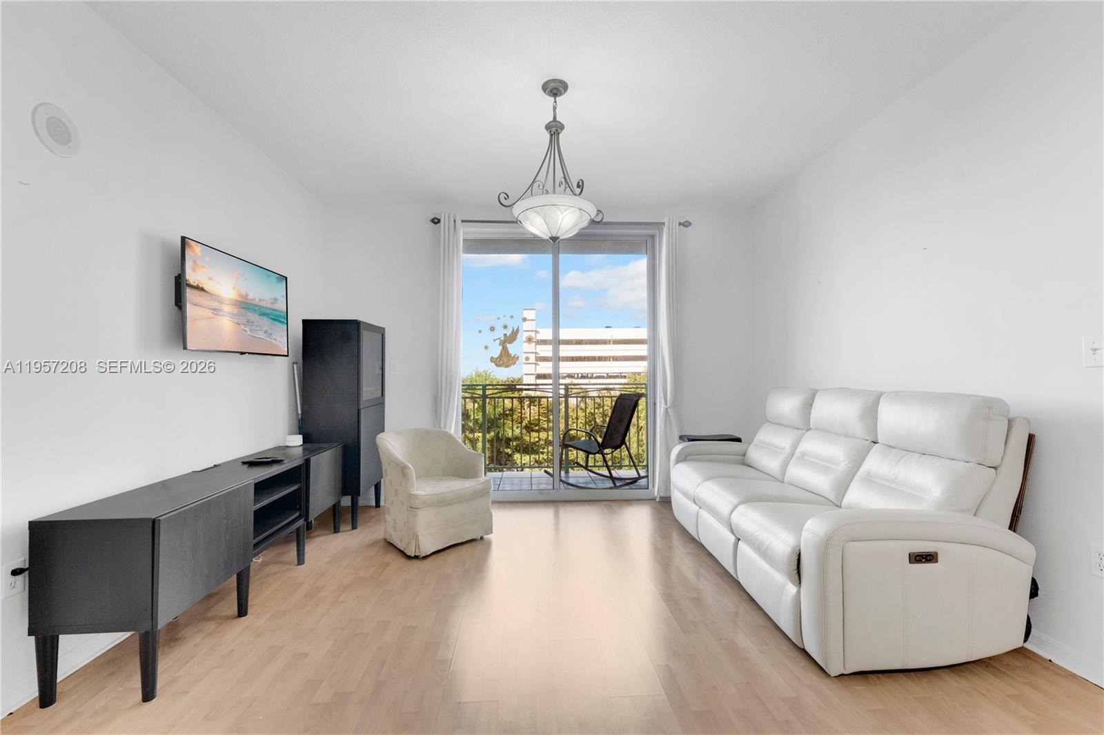 3500 Coral Way, Unit 710 Miami, FL 33145 - Photo 5 of 43 This bright and airy living room features a modern, open-concept layout with light flooring and clean white walls. Large sliding glass doors lead to a private balcony, illuminating the space with natural light and offering a seamless indoor-outdoor feel.