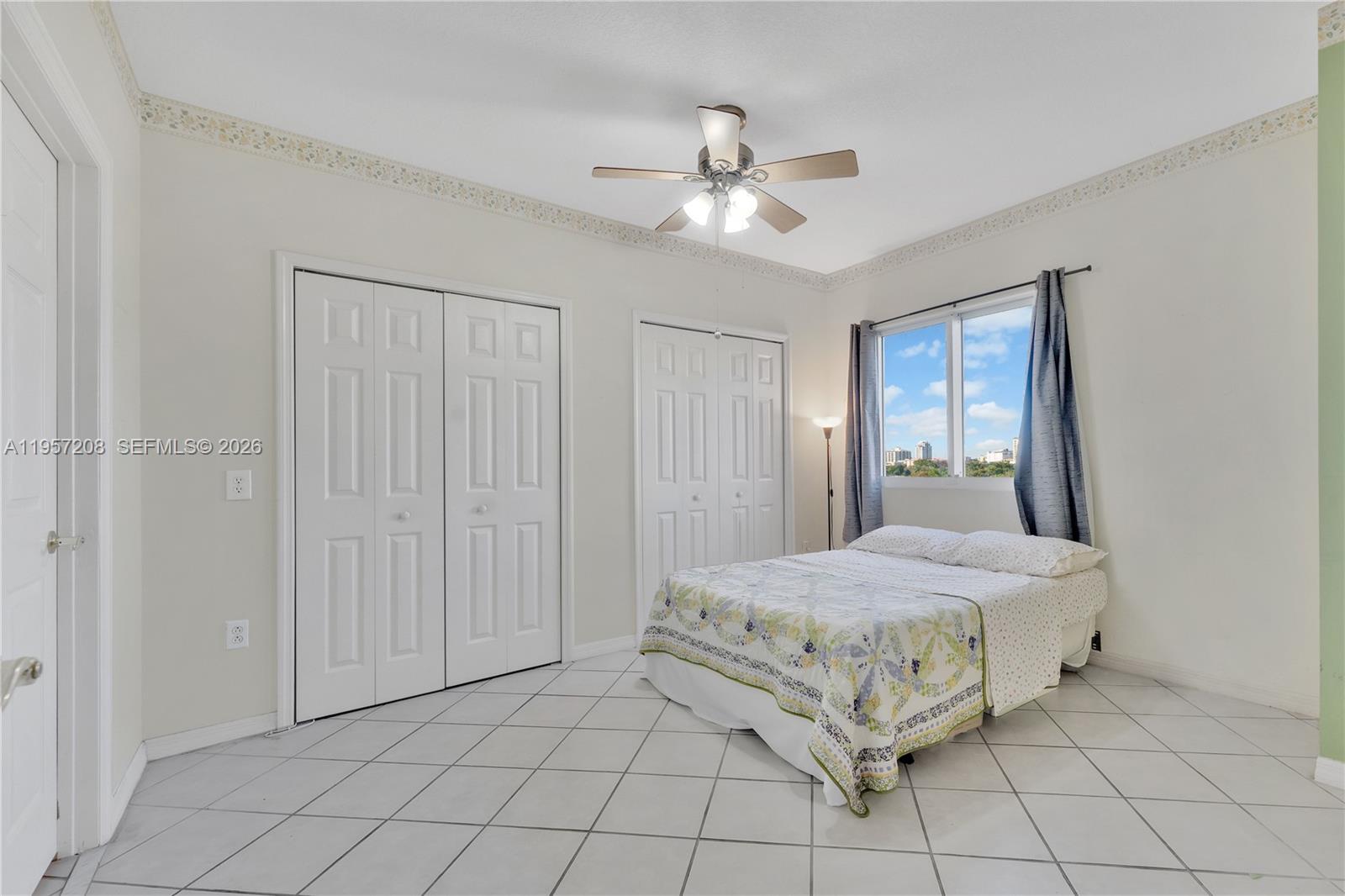 3500 Coral Way, Unit 710 Miami, FL 33145 - Photo 8 of 43 Spacious, light-filled primary bedroom featuring easy-to-clean tile flooring, dual closets for ample storage, and a ceiling fan for year-round comfort.