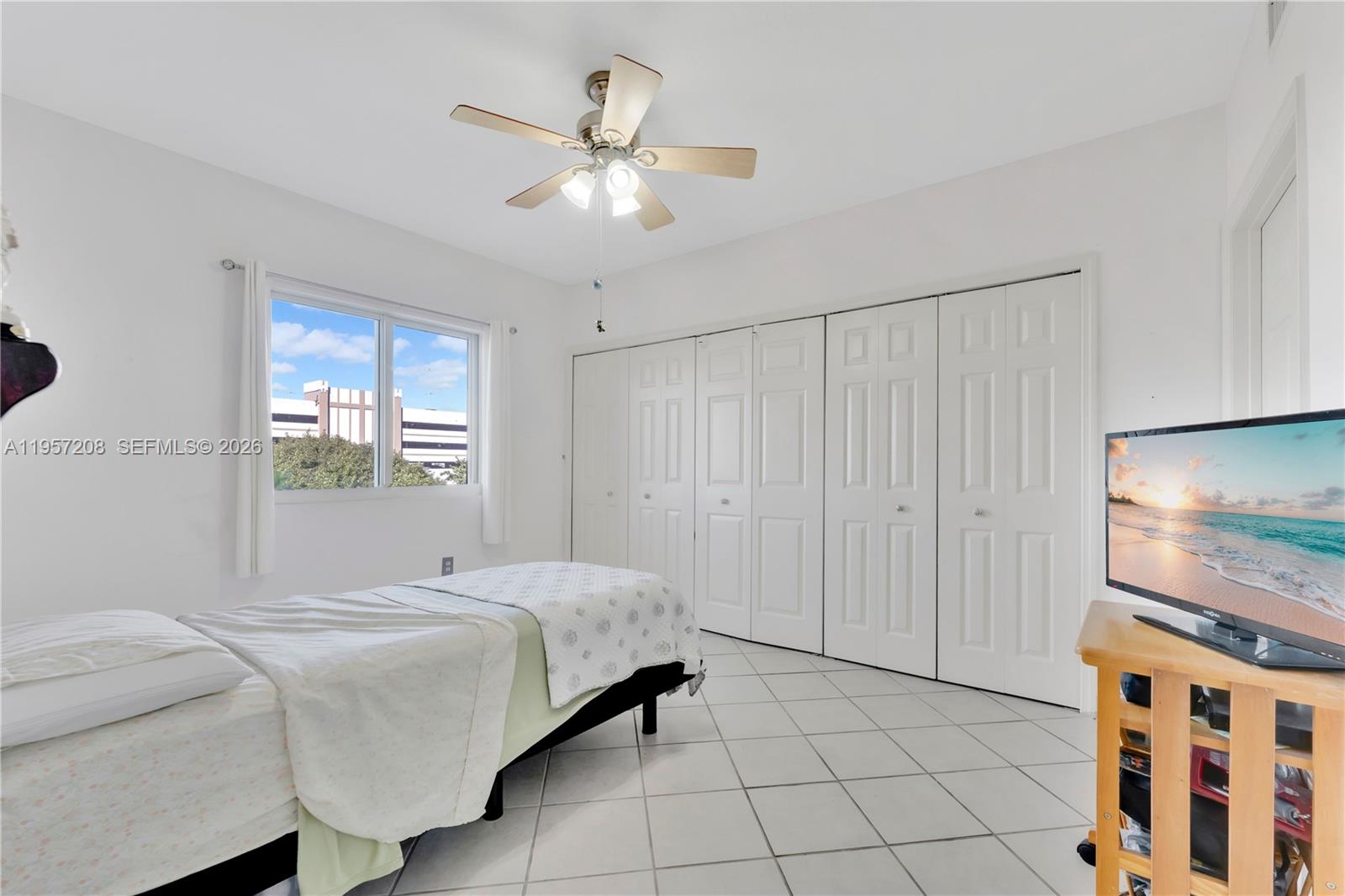 3500 Coral Way, Unit 710 Miami, FL 33145 - Photo 9 of 43 Bright second bedroom featuring a massive wall-to-wall closet, tile floors, and a ceiling fan.