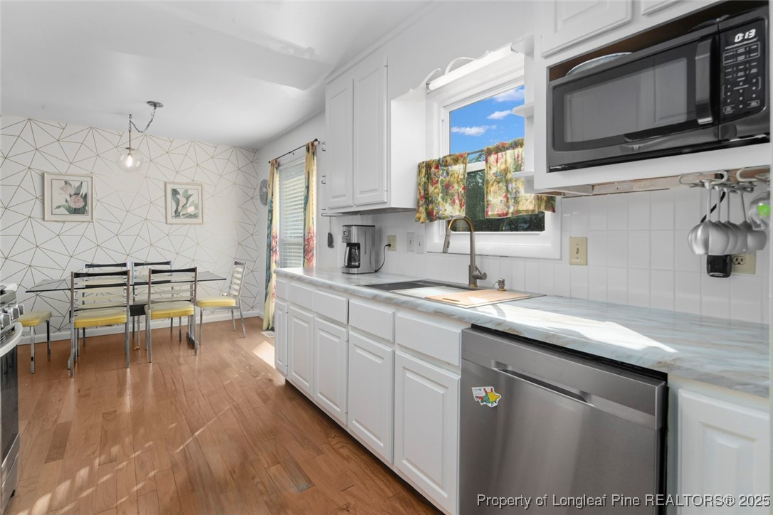 5978 Brookcliff Road Fayetteville, NC 28304 - Photo 9 of 38 a kitchen with stainless steel appliances a sink dishwasher a microwave oven and a stove with wooden floor
