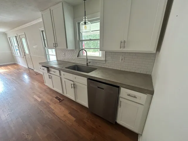 a kitchen with granite countertop a sink a window and cabinets