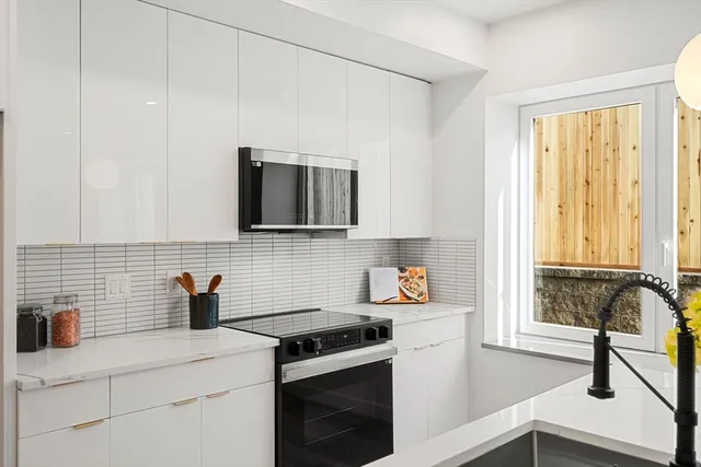 a kitchen with stainless steel appliances white cabinets and a stove top oven