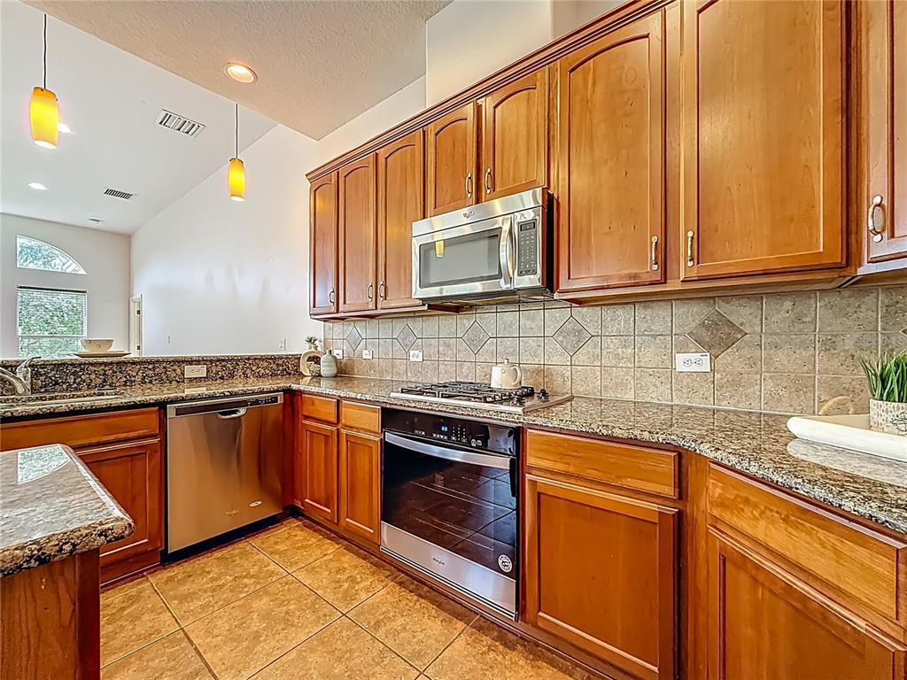 20626 Longleaf Pine Avenue Tampa, FL 33647 - Photo 20 of 86 a kitchen with stainless steel appliances granite countertop wooden cabinets a stove a sink and dishwasher