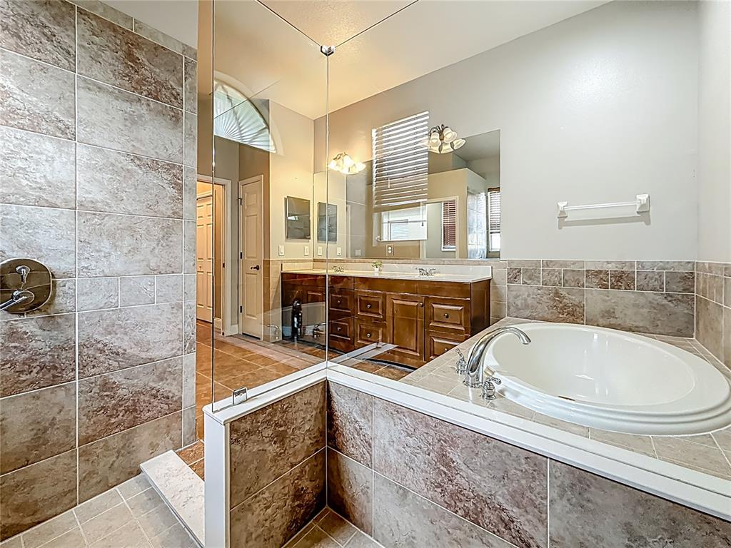 20626 Longleaf Pine Avenue Tampa, FL 33647 - Photo 58 of 86 a bathroom with a tub a double vanity sink a mirror and a shower