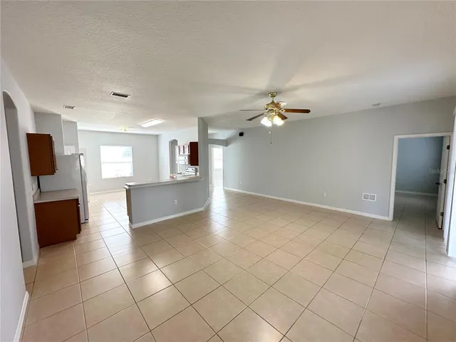 a view of an empty room and a kitchen