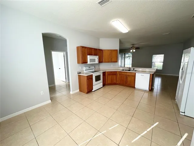 a large kitchen with stainless steel appliances granite countertop a sink and a refrigerator