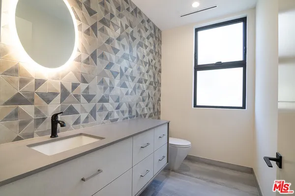 a bathroom with a sink and mirror with toilet