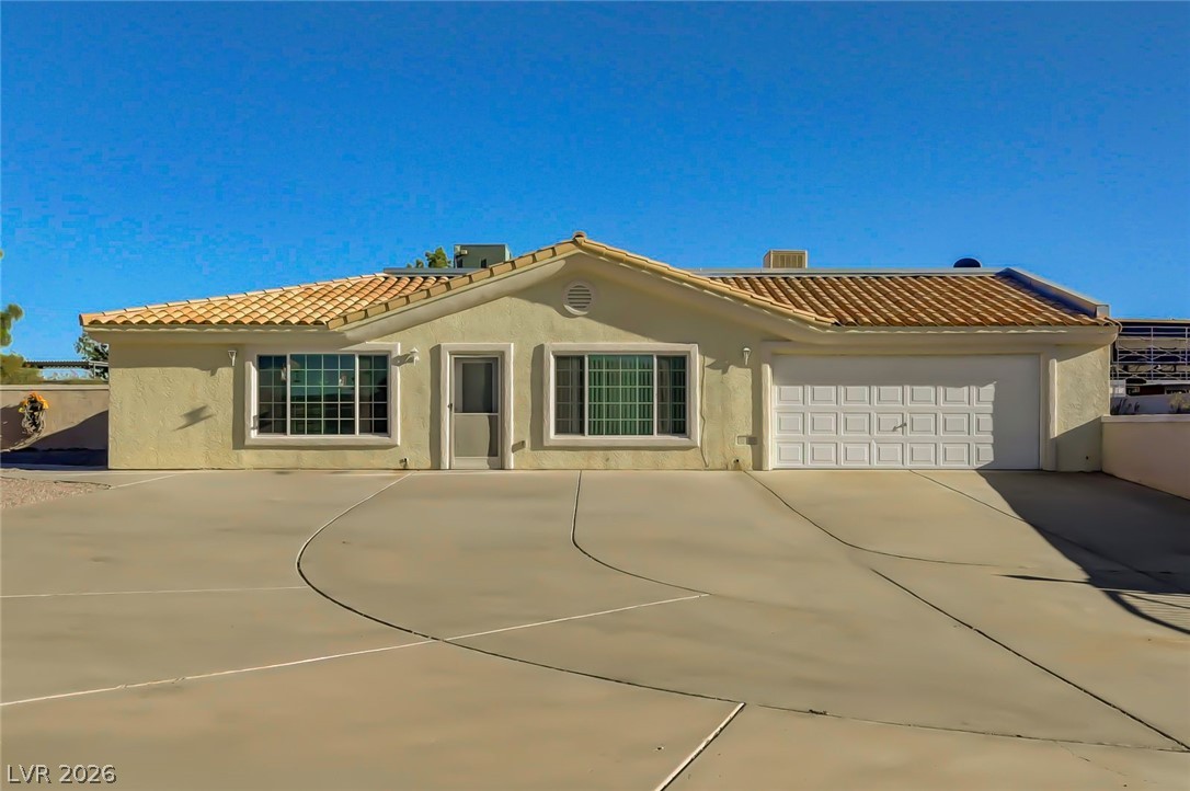 640 North Racetrack Road Henderson, NV 89015 - Photo 14 of 65 A well-maintained stucco facade with a terracotta-tiled roof and a spacious concrete driveway greets visitors.