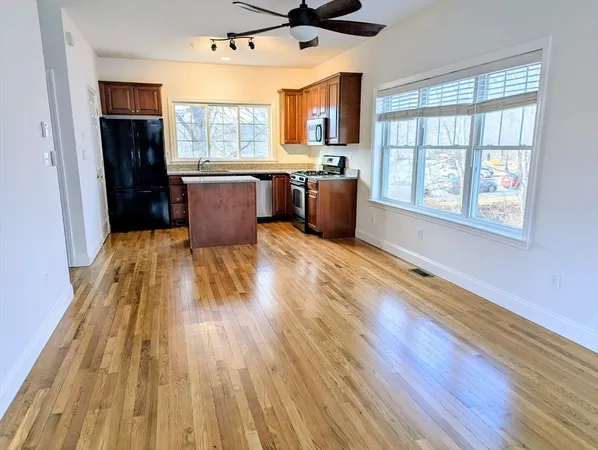 a kitchen with stainless steel appliances granite countertop a refrigerator a sink dishwasher a stove with wooden floor and cabinets next to a window