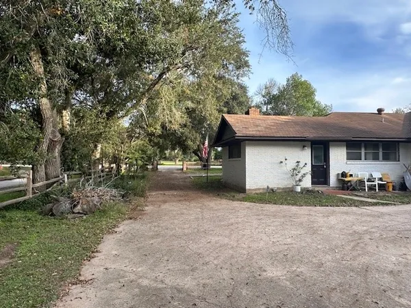 a view of a house with large trees and a car parked