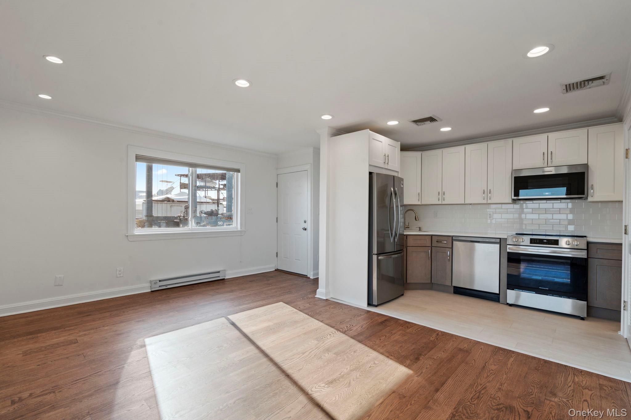 1 Anchorage Way, Unit 101 Freeport, NY 11520 - Photo 8 of 31 a kitchen with stainless steel appliances granite countertop a refrigerator a sink a stove a microwave and island