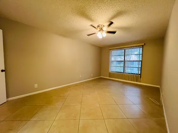 an empty room with a chandelier fan and windows