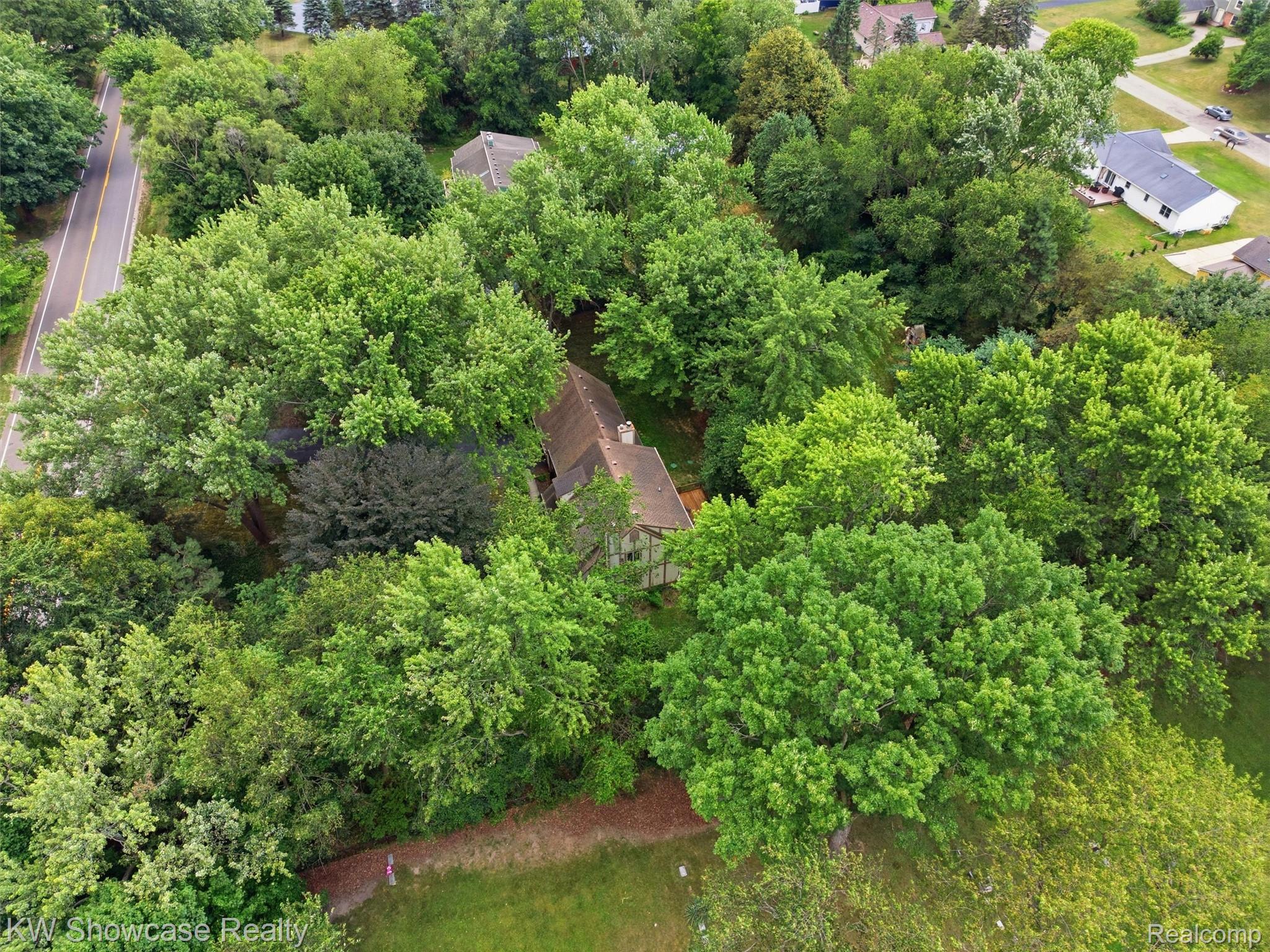 3360 Pleasant Valley Road Brighton, MI 48114 - Photo 54 of 60 Aerial perspective showcasing a property surrounded by mature trees, with a visible roofline and chimney