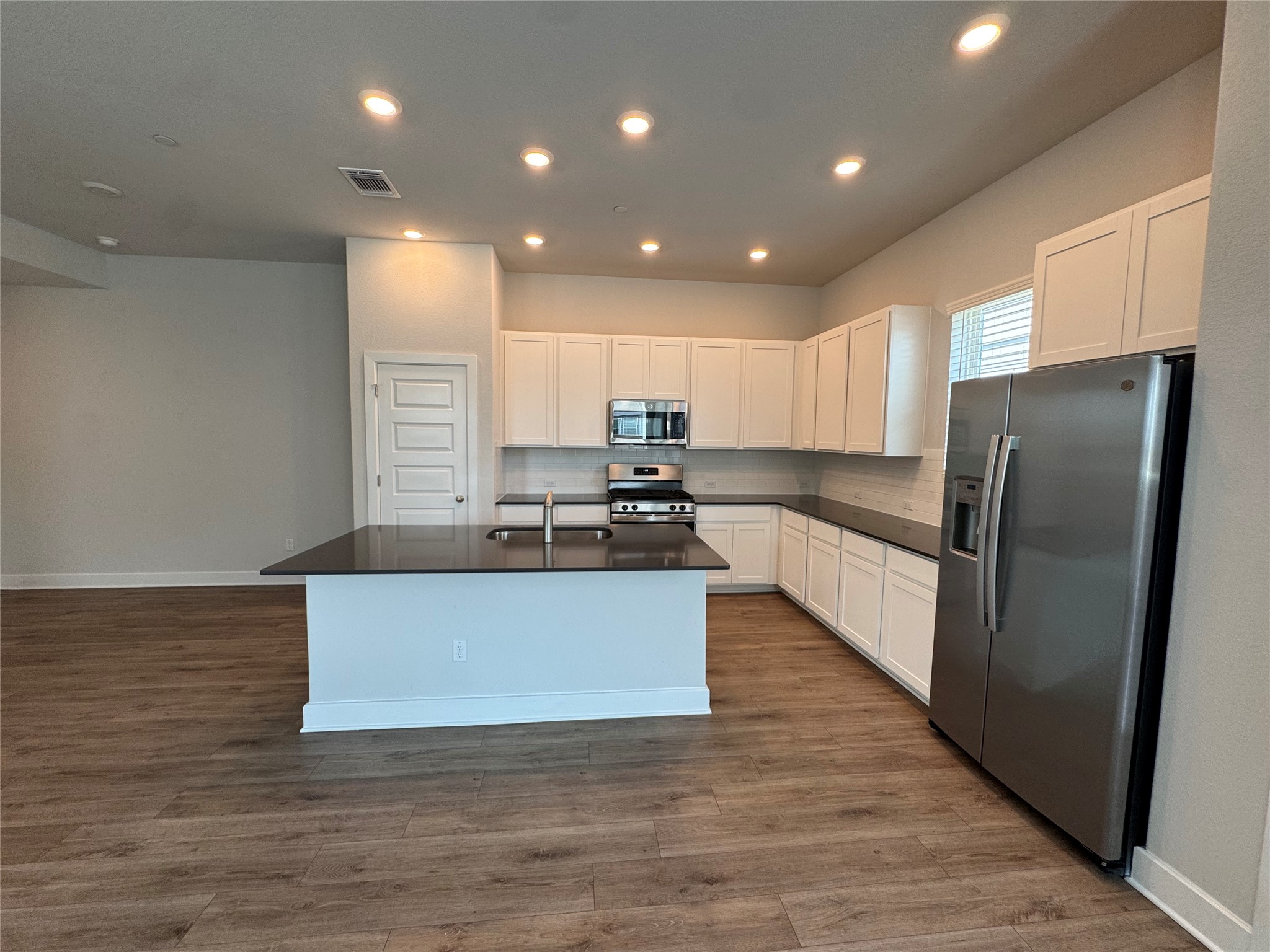 3000 Chisholm Trail Road, Unit 91 Round Rock, TX 78681 - Photo 6 of 27 A well-lit kitchen with sleek dark counters and wood-look flooring anchors the open living space.