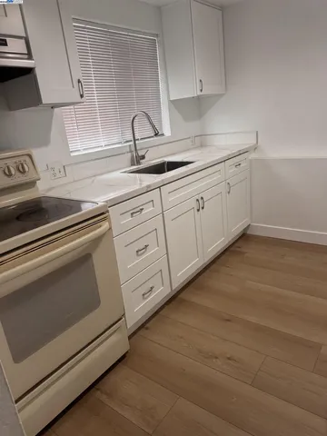 a kitchen with white cabinets and sink