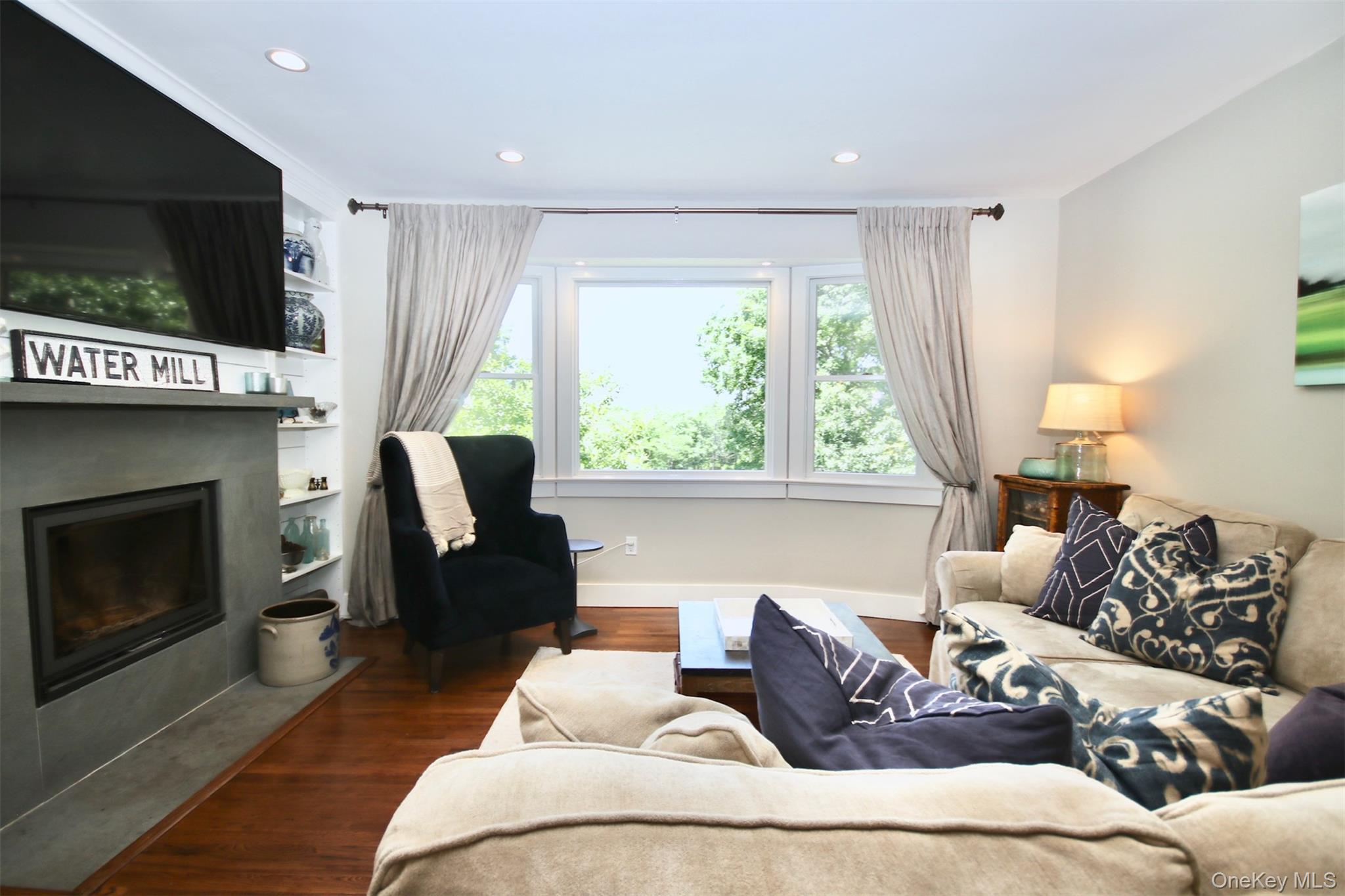 28 Old Trail Road Water Mill, NY 11976 - Photo 8 of 25 a living room with furniture a flat screen tv and a fireplace