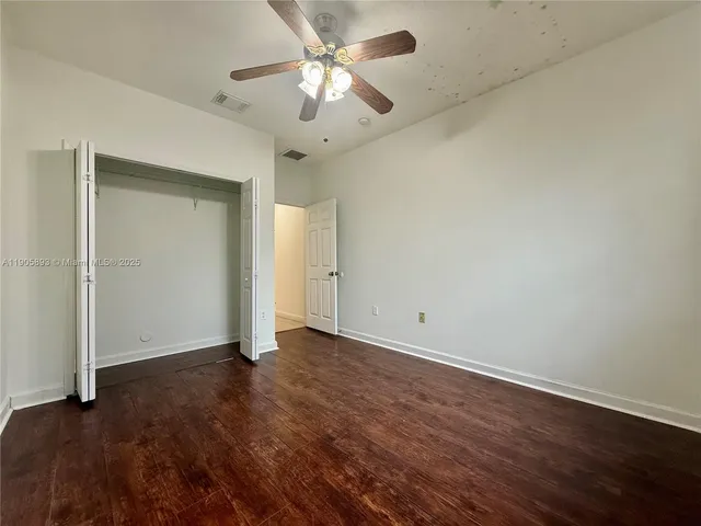 an empty room with wooden floor and fan