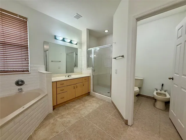 a spacious bathroom with a tub sink toilet and mirror