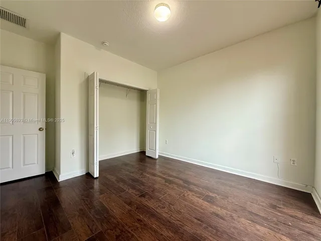 a view of an empty room with wooden floor and closet