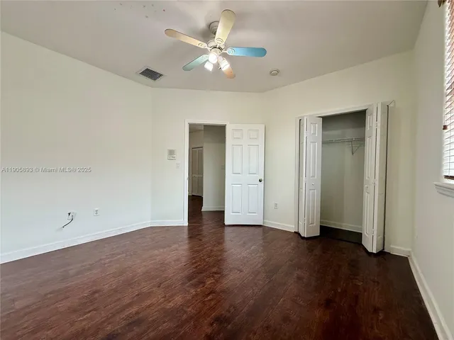 an empty room with wooden floor and a ceiling fan