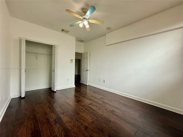 an empty room with wooden floor and a ceiling fan
