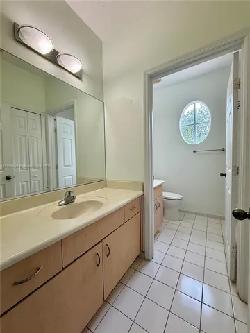 a spacious bathroom with a granite countertop sink a toilet and a mirror