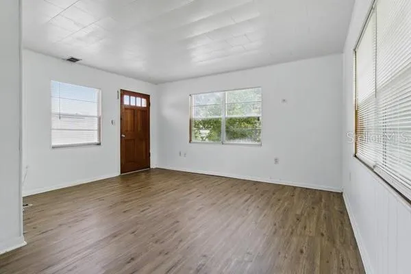 an empty room with wooden floor and windows