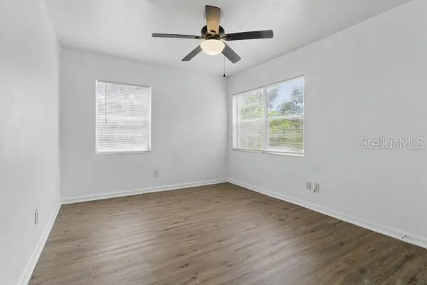a view of an empty room with wooden floor and a window