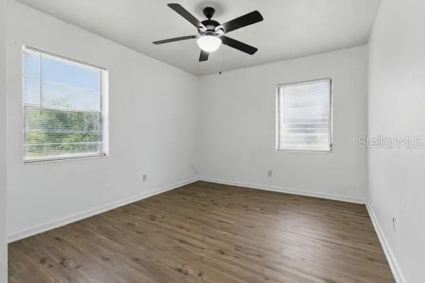 a view of empty room with wooden floor and fan