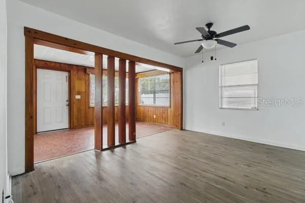 an empty room with wooden floor fan and windows