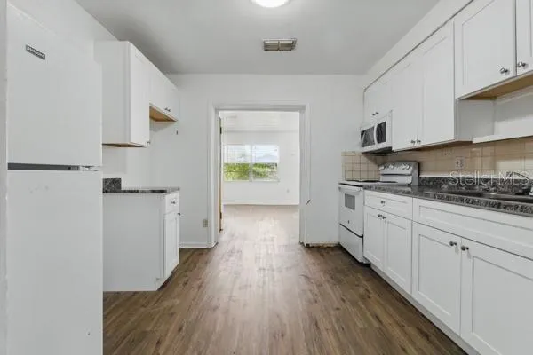 a kitchen with cabinets and wooden floor