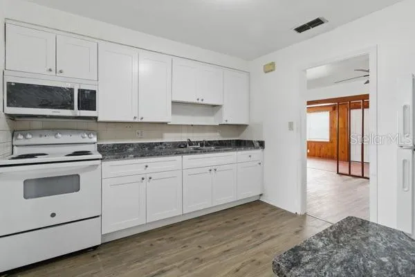 a kitchen with granite countertop white cabinets and white appliances