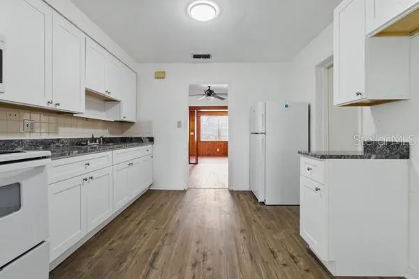 a kitchen with granite countertop white cabinets and white appliances