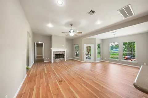 a view of an empty room with wooden floor fireplace and a window
