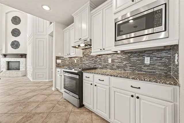 a kitchen with stainless steel appliances granite countertop a stove a microwave and a sink