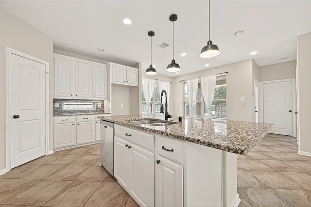 a kitchen with kitchen island granite countertop a sink cabinets and stainless steel appliances