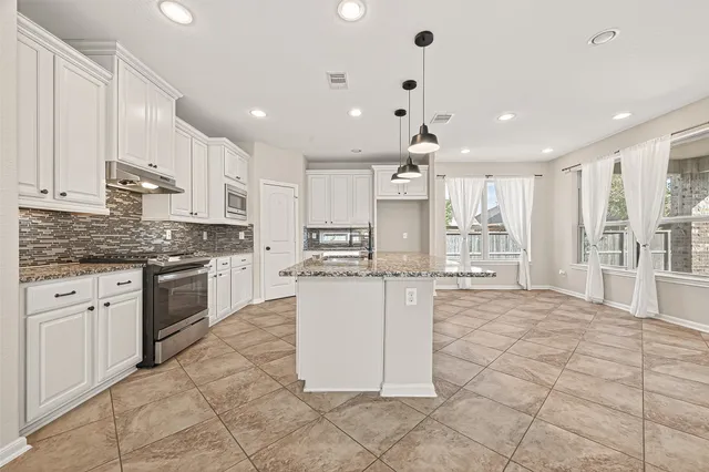 a kitchen with a stove a sink dishwasher a refrigerator and white cabinets with wooden floor