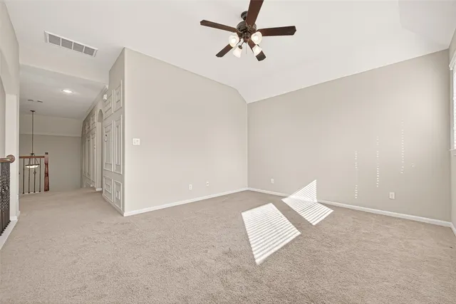 an empty room with a ceiling fan and carpet