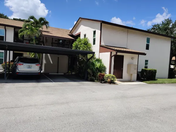 front view of a house with potted plants and a car parked in front of it