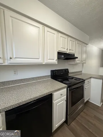 a kitchen with stainless steel appliances granite countertop white cabinets and a stove top oven