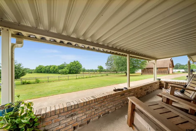 a view of a patio with chairs and table next to a yard