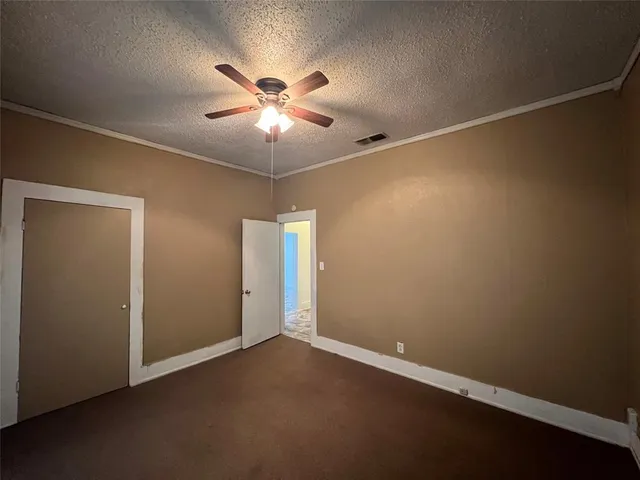an empty room with a fan & a window