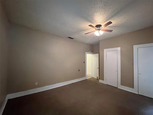 an empty room with a chandelier fan and windows