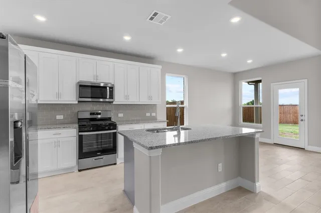 a large kitchen with stainless steel appliances granite countertop a lot of counter space cabinets and a refrigerator