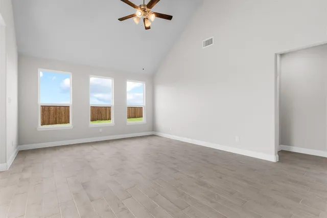 a view of an empty room with chandelier fan and fire place