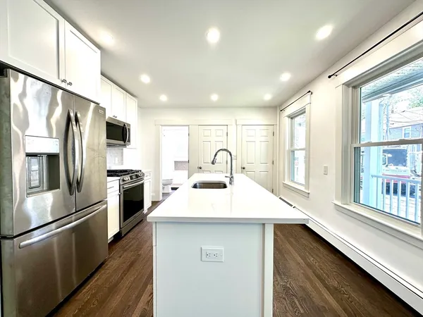 a kitchen with stainless steel appliances a stove refrigerator sink and a large window