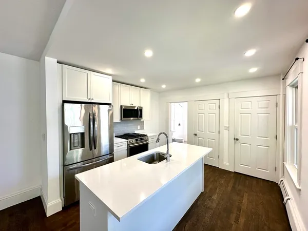 a large kitchen with a refrigerator a sink dishwasher with a dining table and chairs with wooden floor