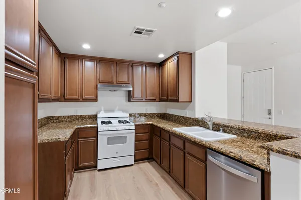 a kitchen with granite countertop stainless steel appliances sink stove microwave and cabinets