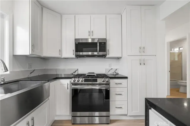 a kitchen with stainless steel appliances granite countertop a stove a microwave and a white cabinets